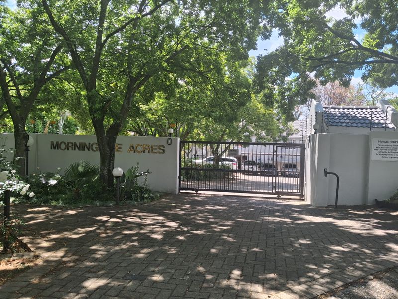 The entrance to Morning Side Acres complex, featuring a secure gated access point, paved driveway, and established perimeter wall with electric fencing.