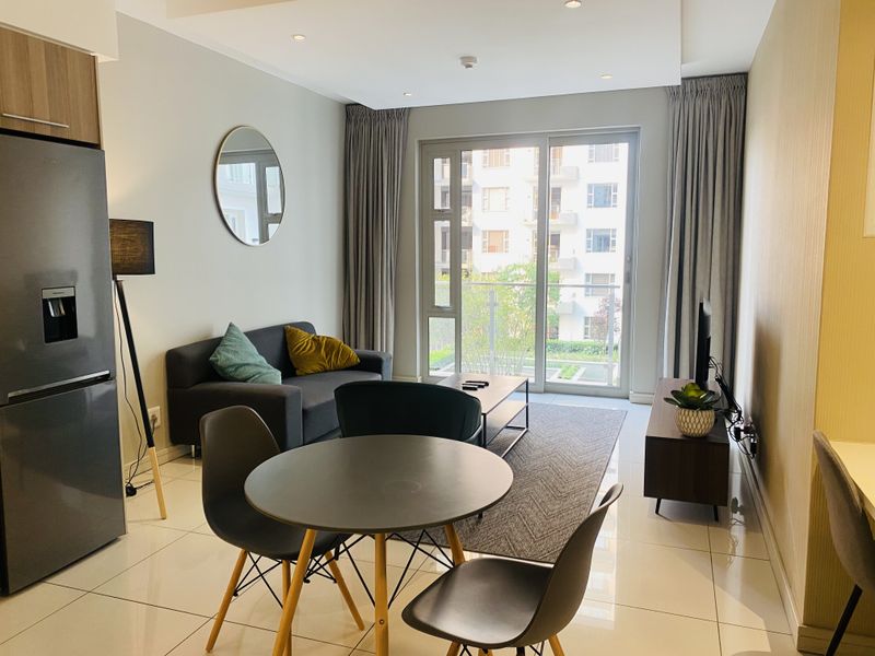 Modern open-plan living area featuring tiled floors, recessed lighting, and a sliding glass door leading to a private balcony.