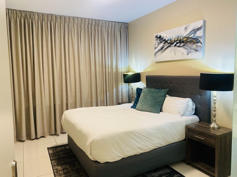 A well-maintained bedroom featuring neutral wall tones, tiled flooring, and full-length curtains, creating a comfortable and inviting sleeping space.