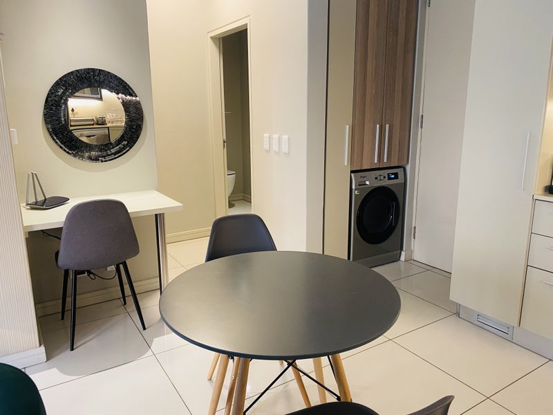 Open plan living area featuring tiled flooring and integrated laundry cabinetry with a built-in washing machine.