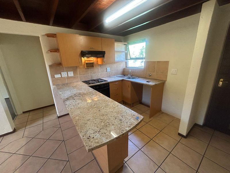 Functional kitchen featuring granite countertops, built-in oven with extractor fan, tiled backsplash, and exposed beam ceiling, offering a practical layout for updates.