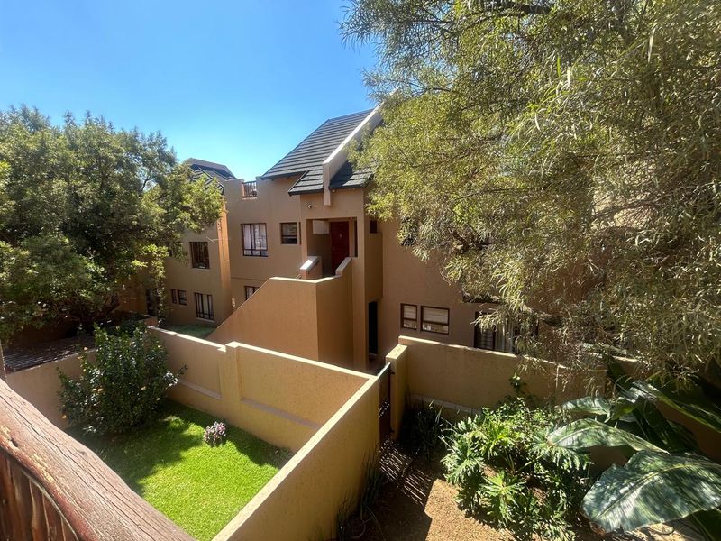 A view of the rear exterior of the apartment complex, featuring a private garden area, boundary walls, and tiled roofing.