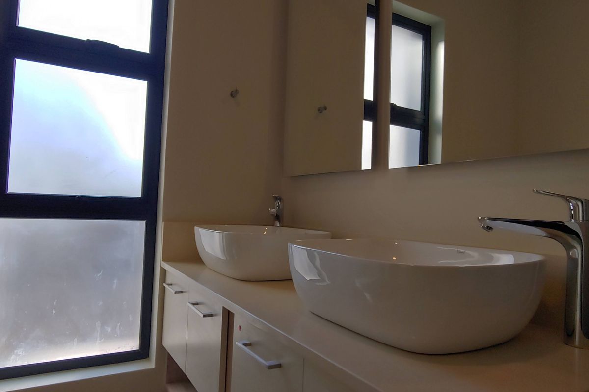 Modern bathroom featuring a double vanity with vessel sinks, chrome mixer taps, and a large wall-mounted mirror.