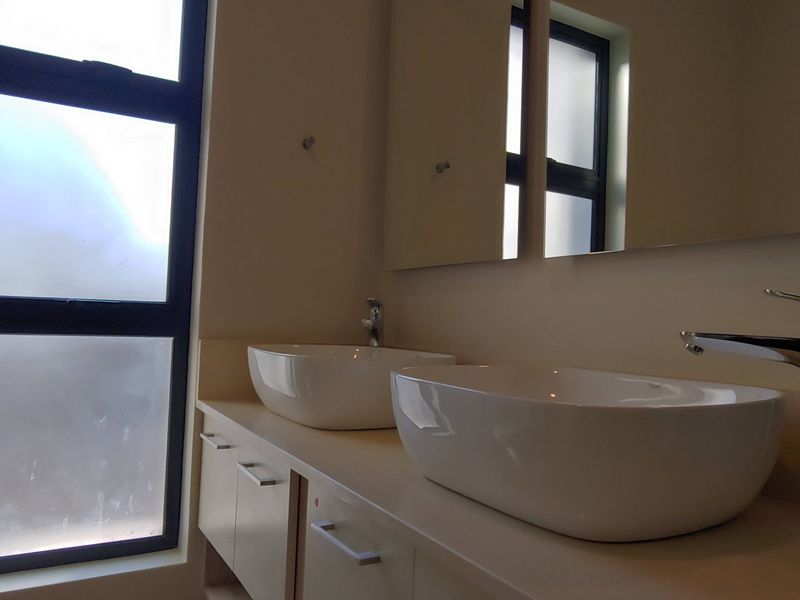 Modern bathroom featuring a double vanity with vessel sinks, chrome mixer taps, and a large wall-mounted mirror.