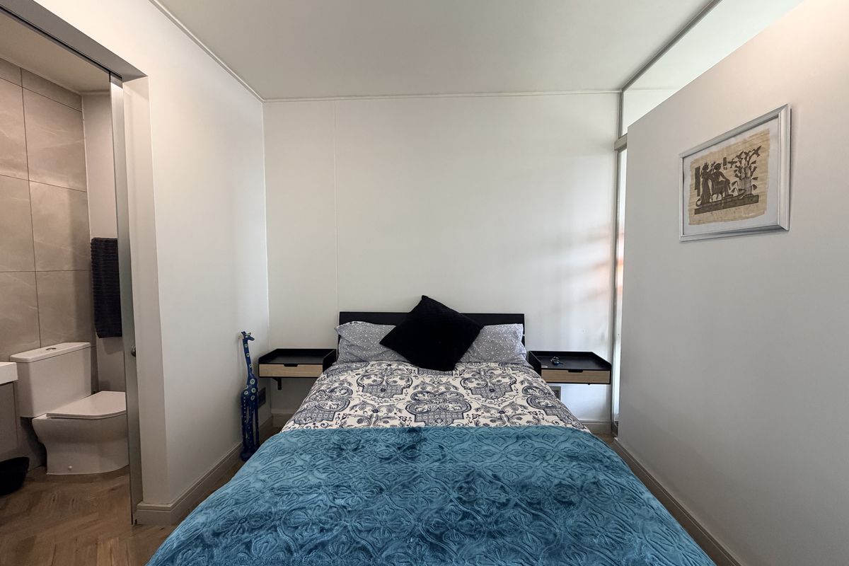 A well-maintained bedroom featuring modern floating bedside tables, herringbone flooring, and direct access to an en-suite bathroom.