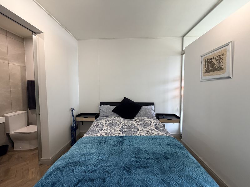 A well-maintained bedroom featuring modern floating bedside tables, herringbone flooring, and direct access to an en-suite bathroom.