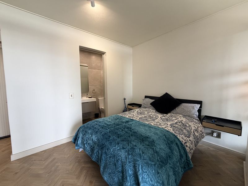 A well-maintained bedroom featuring elegant herringbone timber flooring and a convenient en-suite bathroom with modern fixtures.