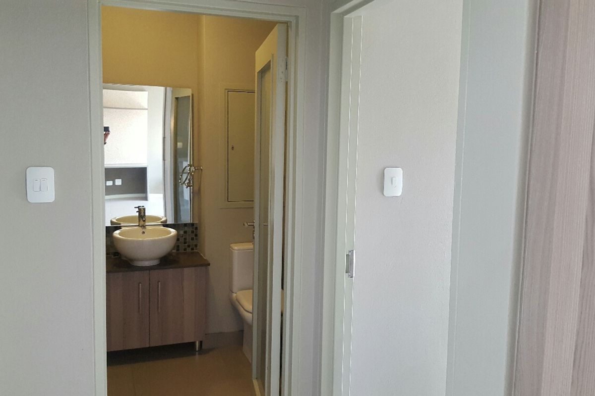 A view into a clean, modern bathroom featuring a vanity with a vessel sink, mirror, and toilet.