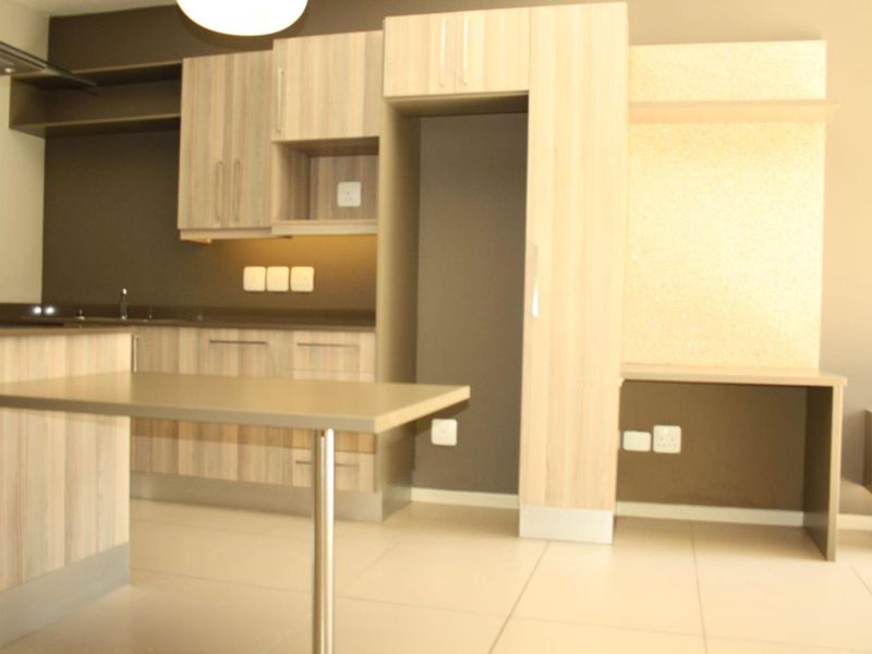 Modern kitchen featuring light wood-finish cabinetry, integrated breakfast bar, and tiled flooring, offering a clean and functional space for culinary activities.