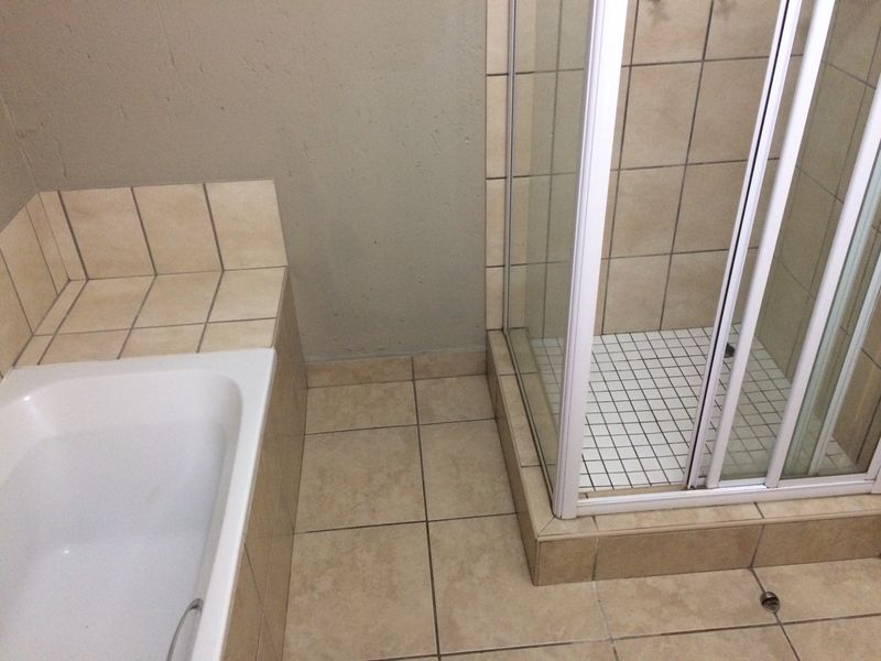 A functional bathroom featuring a built-in bathtub and a separate tiled shower enclosure with glass doors.