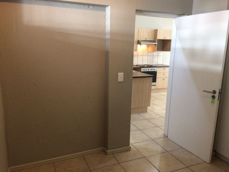 A view from a hallway looking into a kitchen area featuring tiled flooring and neutral wall finishes.