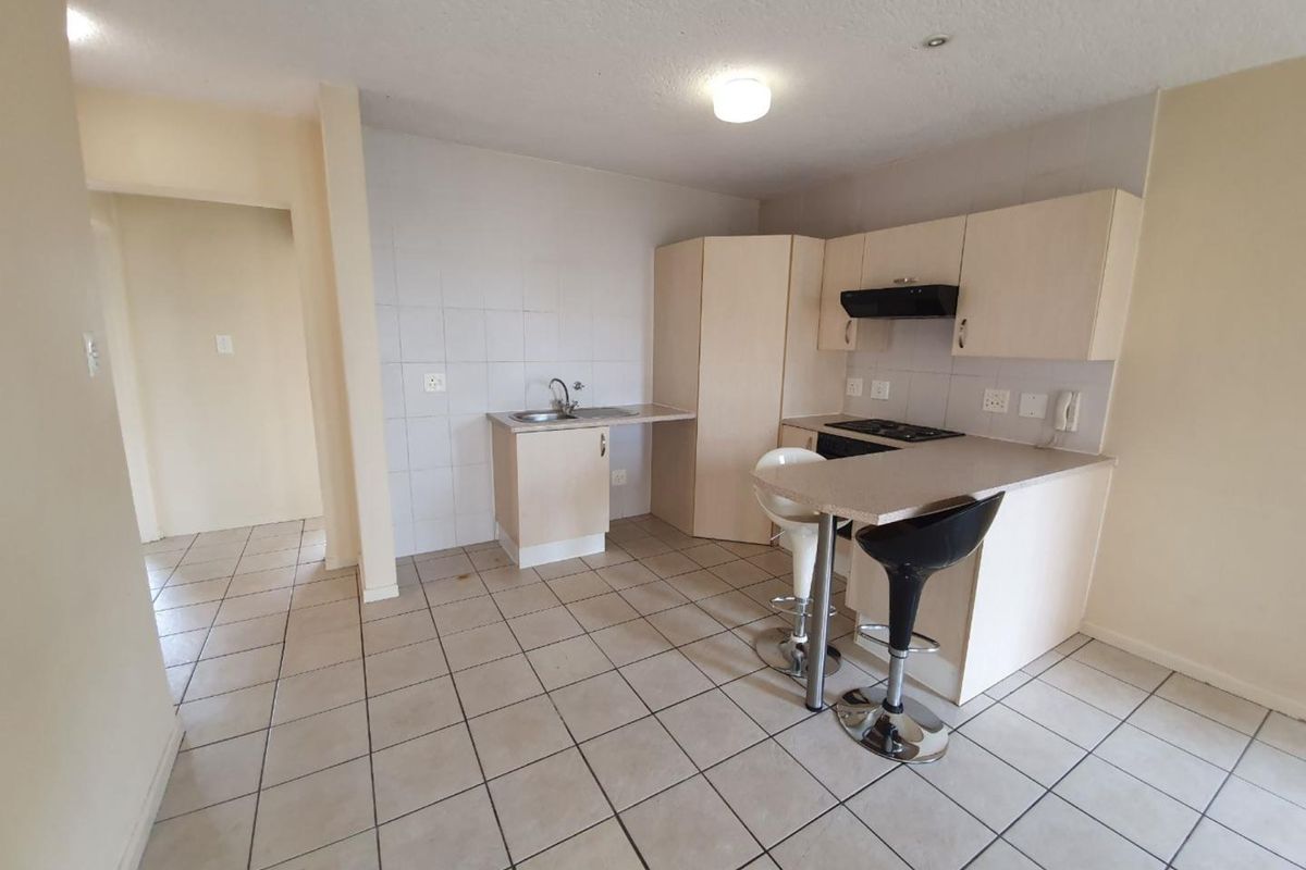 A functional kitchen featuring built-in cabinetry, laminate countertops, a stainless steel sink, and a built-in hob with an extractor fan.