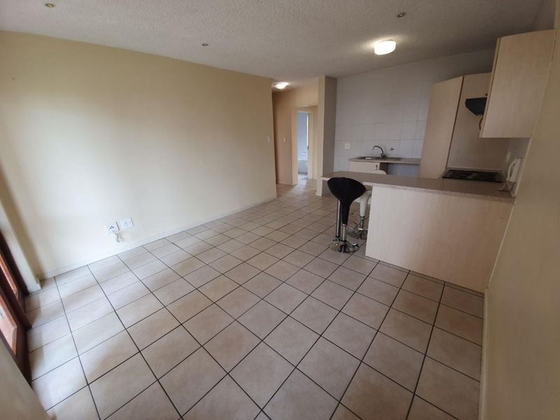 Open plan living area featuring tiled flooring and a functional kitchen with built-in cabinetry, breakfast bar, and integrated hob.