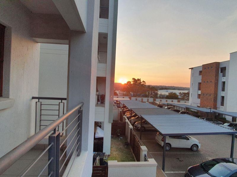 A view from an apartment balcony overlooking the complex parking area and surrounding neighborhood at sunset.