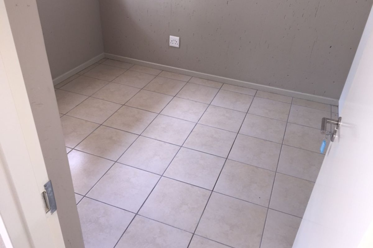 An empty bedroom featuring neutral ceramic floor tiles and painted walls, providing a blank canvas for personalization.