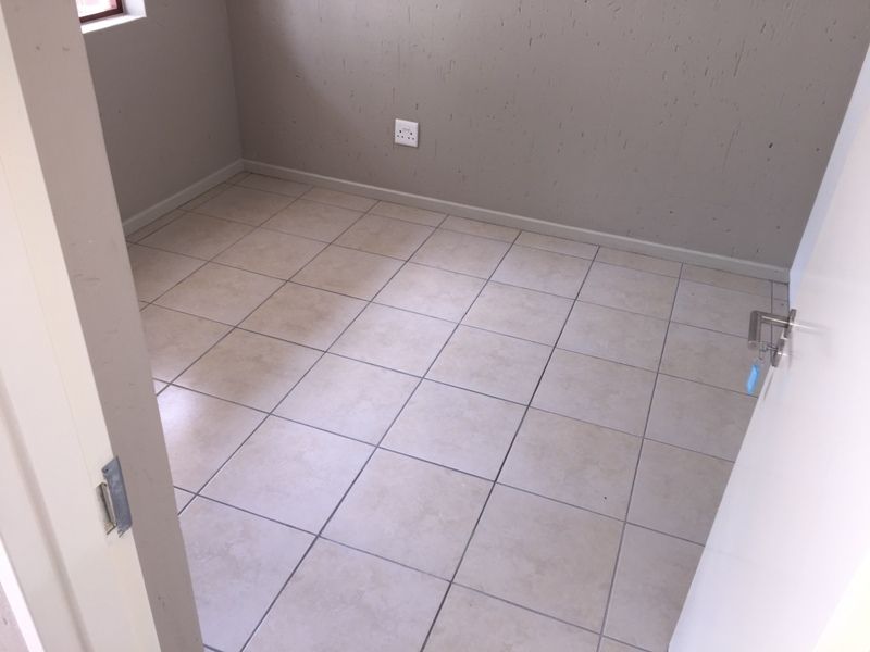 An empty bedroom featuring neutral ceramic floor tiles and painted walls, providing a blank canvas for personalization.