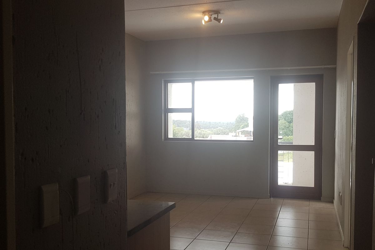 An empty living area featuring tiled flooring, natural light from a large window, and direct access to an outdoor space.