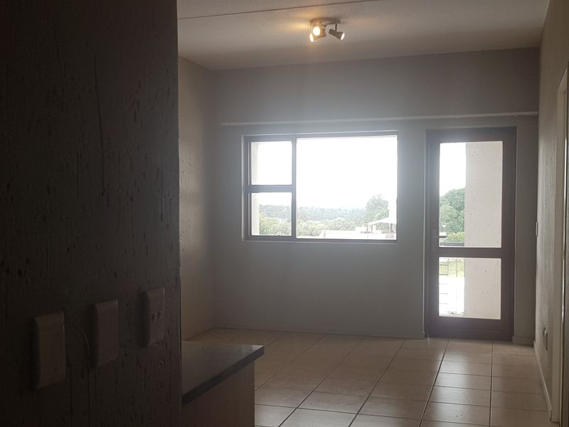 An empty living area featuring tiled flooring, natural light from a large window, and direct access to an outdoor space.