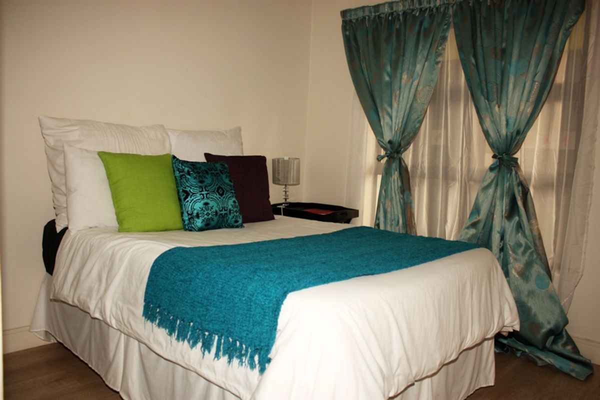 A standard bedroom featuring neutral walls and laminate flooring, providing a functional and comfortable sleeping space.