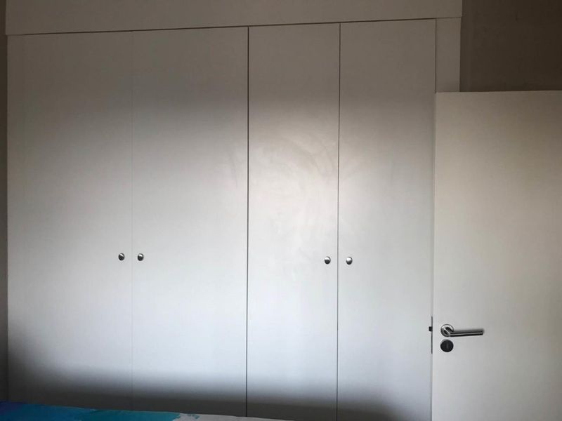 A bedroom featuring white built-in wardrobes with simple hardware and a standard internal door.