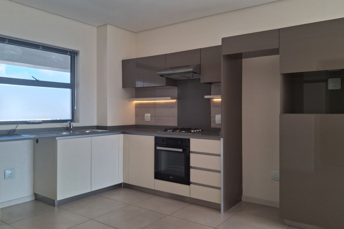 Modern kitchen featuring sleek two-tone cabinetry, built-in gas hob, electric oven, extractor fan, and tiled flooring in a clean, contemporary layout.