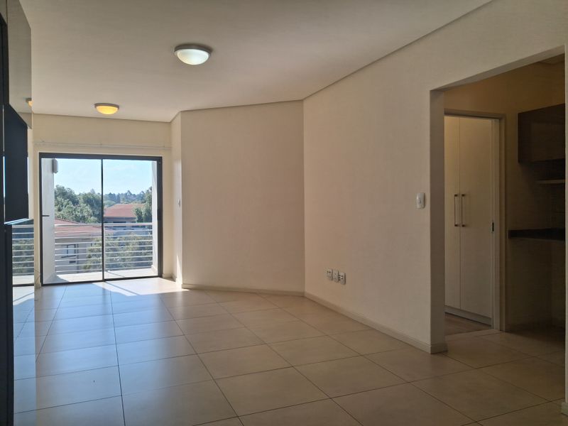 Spacious open-plan living area featuring neutral tiled flooring, ample natural light, and direct access to a private balcony.