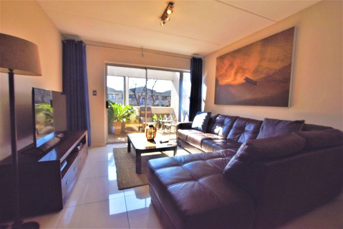 A comfortable living room featuring tiled flooring and a large sliding glass door that provides access to an outdoor balcony area.