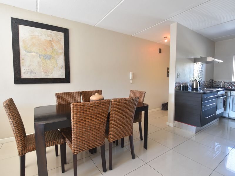 Open plan living and dining area featuring tiled flooring and a modern kitchen with built-in cabinetry, oven, and extractor fan.