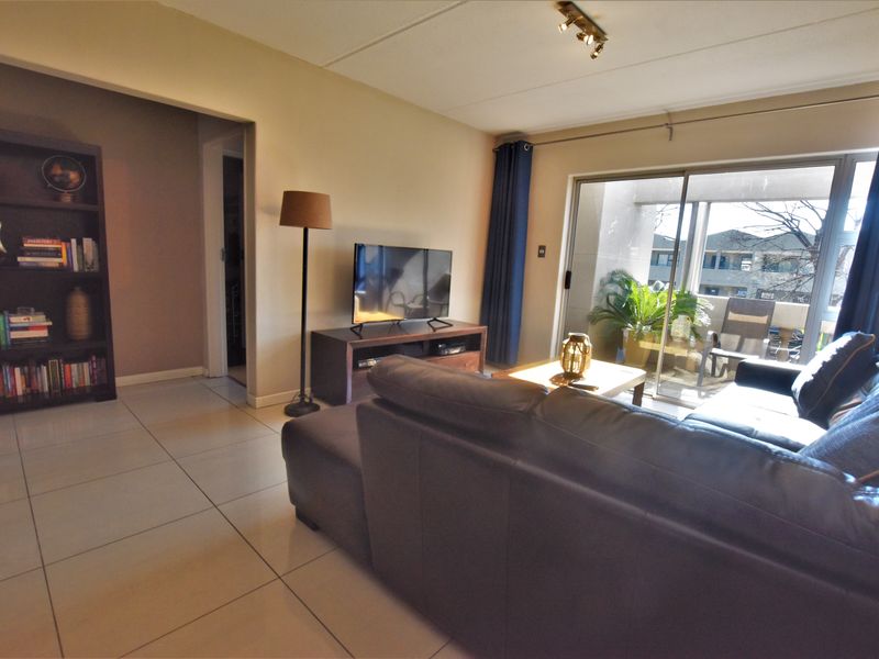 A bright living room featuring tiled flooring and a large sliding glass door that provides access to an outdoor balcony area.