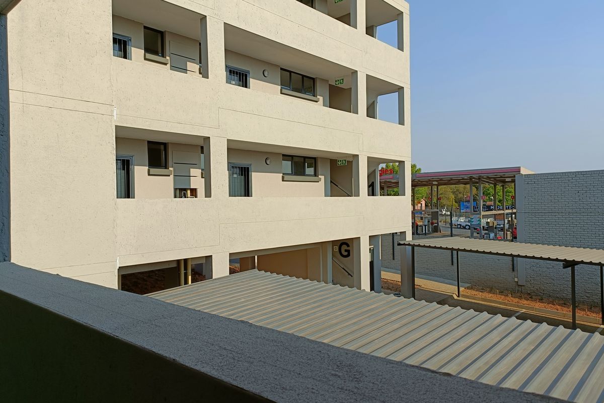 Exterior view of a multi-story apartment building featuring concrete facade, open stairwell access, and covered parking structures.