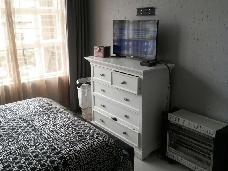 A bedroom featuring textured wall finishes and large windows with curtain tracks, providing natural light to the space.