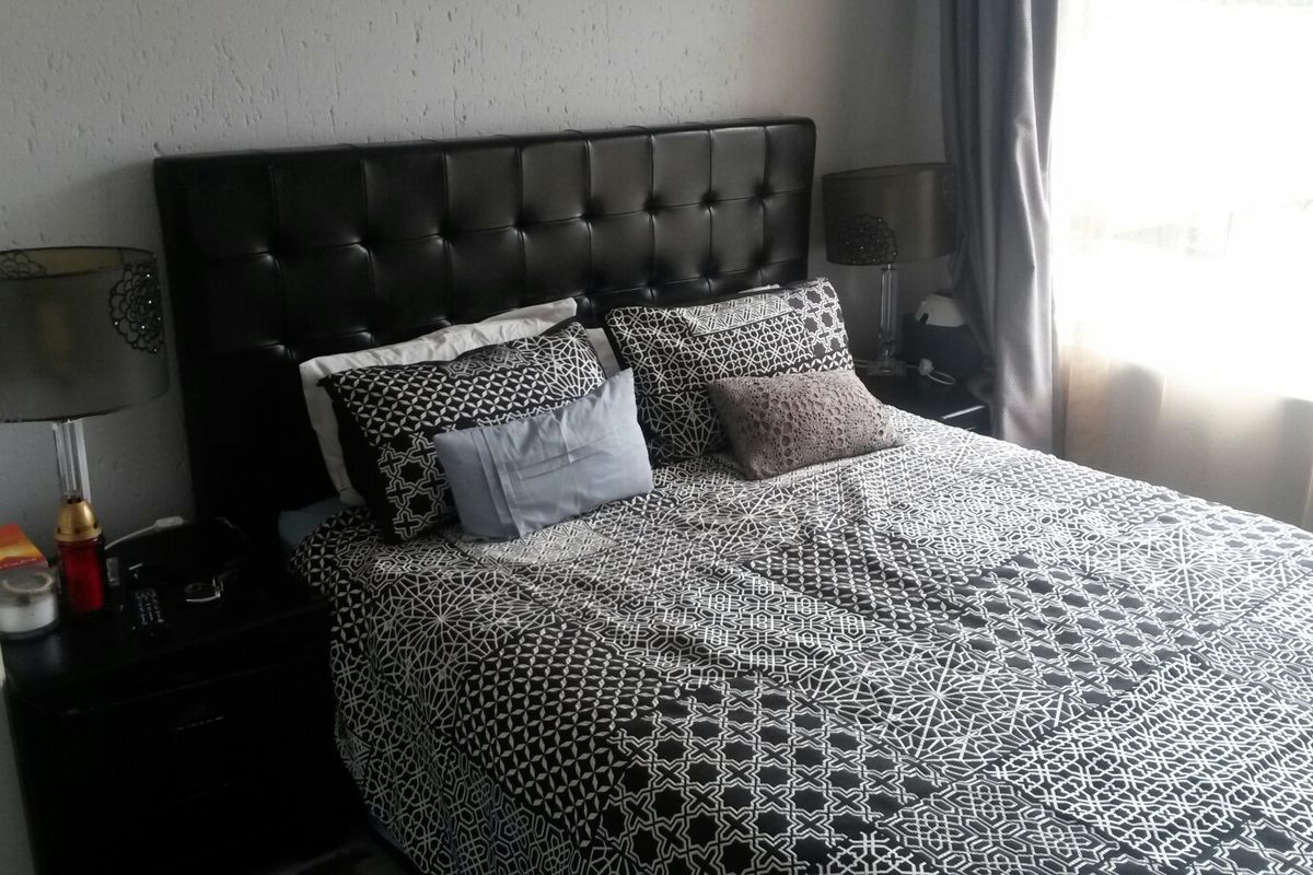 A bedroom featuring textured wall finishes and natural light from the window.