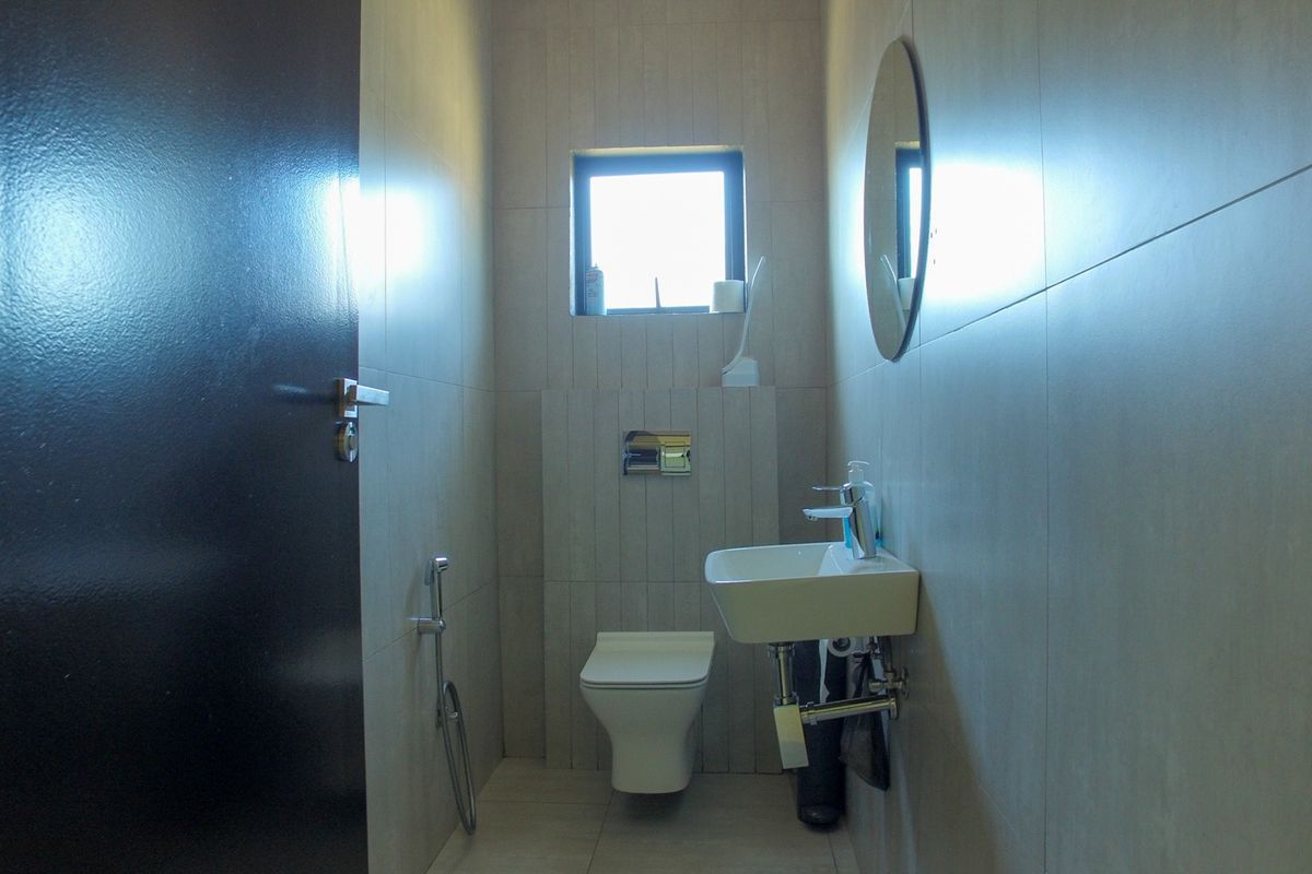 A modern, compact guest bathroom featuring neutral wall tiles, a wall-mounted basin, and a wall-hung toilet with a concealed cistern.
