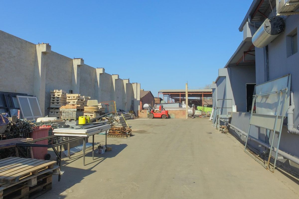 An industrial rear yard area featuring a concrete surface, perimeter walling, and access to the side of the main industrial building structure.
