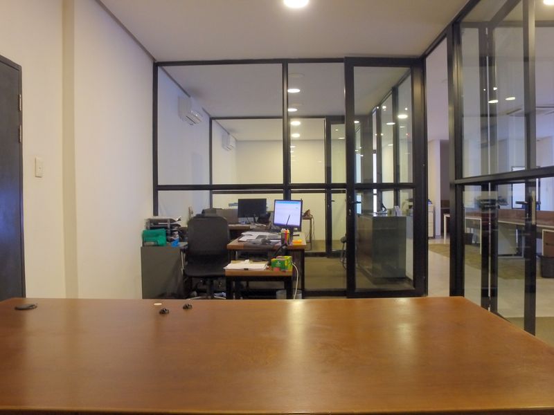 Modern office space featuring black metal framed glass partitions, recessed lighting, and integrated air conditioning, providing a professional and open work environment.