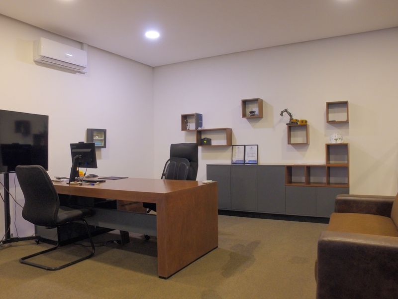 A professional office space featuring built-in cabinetry, a glass partition wall, and a split-system air conditioning unit.