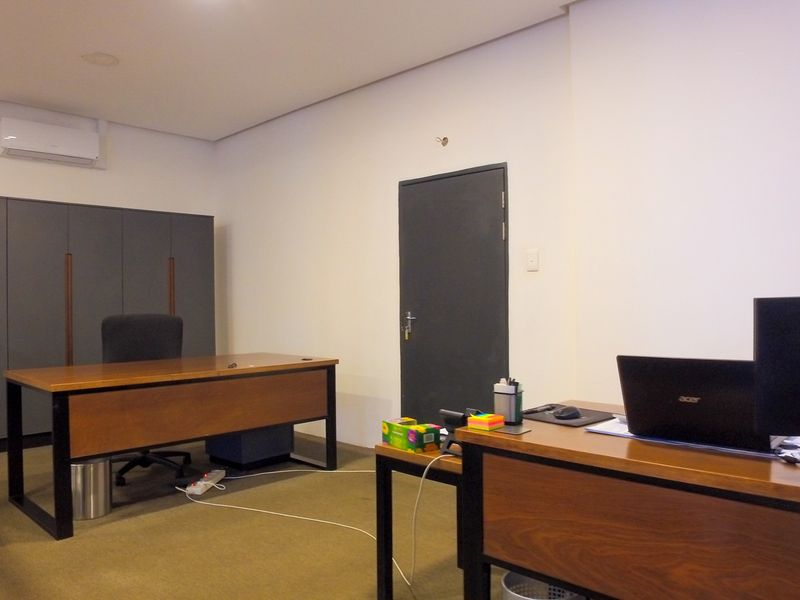 A functional office space featuring built-in storage cabinetry, carpeted flooring, and a wall-mounted split-system air conditioning unit.