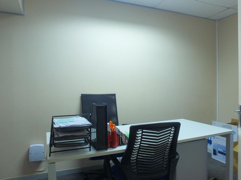 A functional office space featuring neutral wall finishes, a suspended ceiling, and carpet flooring, suitable for a professional work environment.