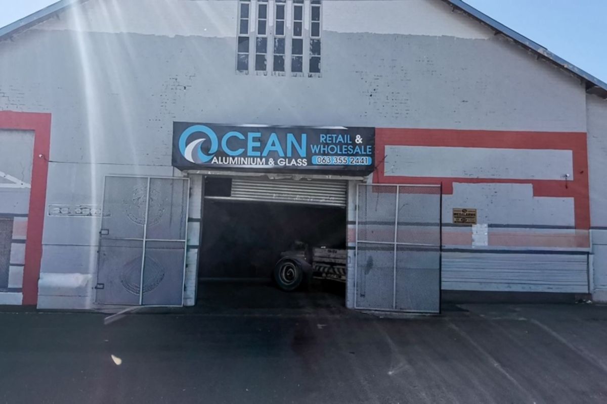 Front elevation of an industrial warehouse building featuring a large roller shutter entrance and prominent business signage.