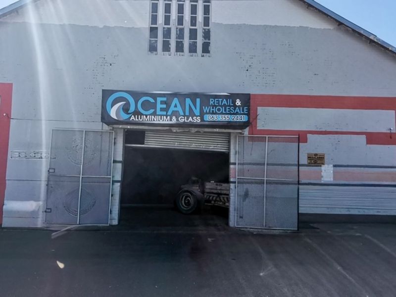 Front elevation of an industrial warehouse building featuring a large roller shutter entrance and prominent business signage.
