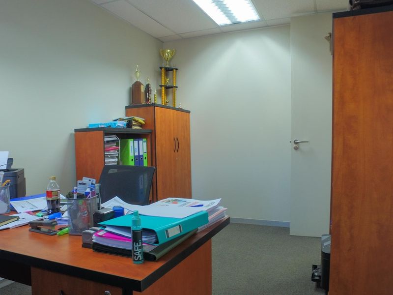 A functional office space featuring carpeted flooring, recessed ceiling lighting, and a standard internal door.