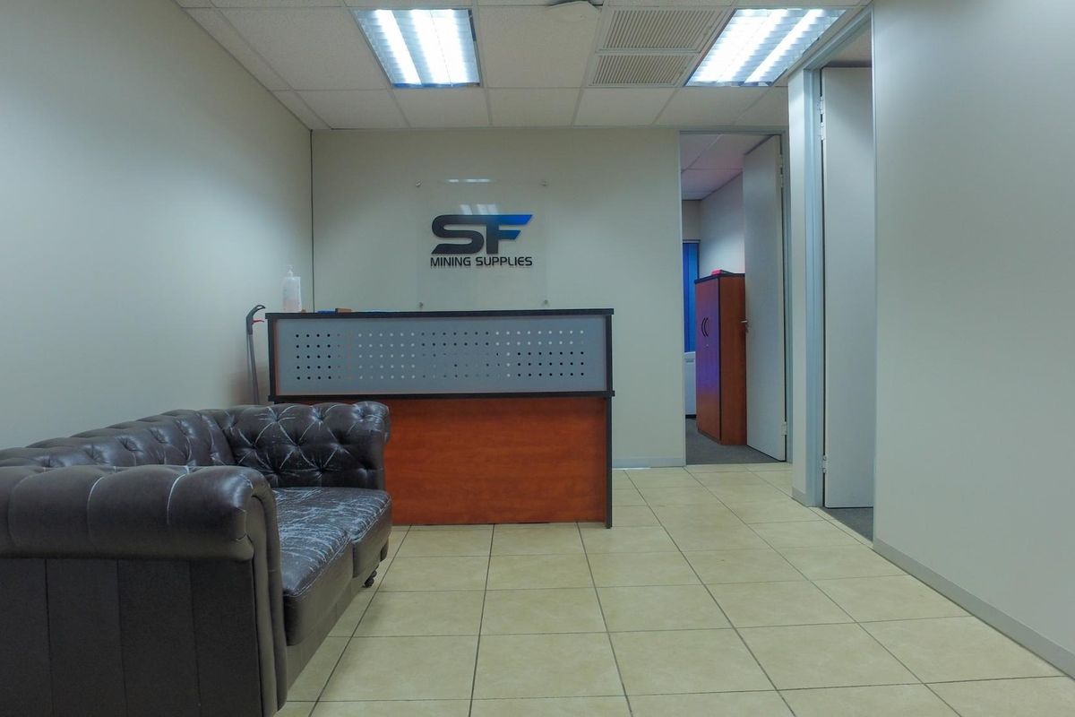 Professional office reception area featuring tiled flooring, recessed ceiling lighting, and a built-in reception desk.