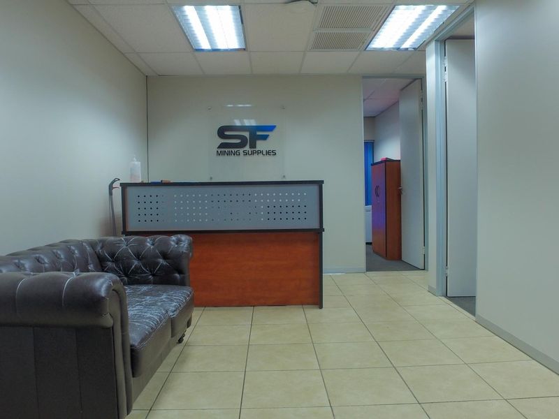 Professional office reception area featuring tiled flooring, recessed ceiling lighting, and a built-in reception desk.