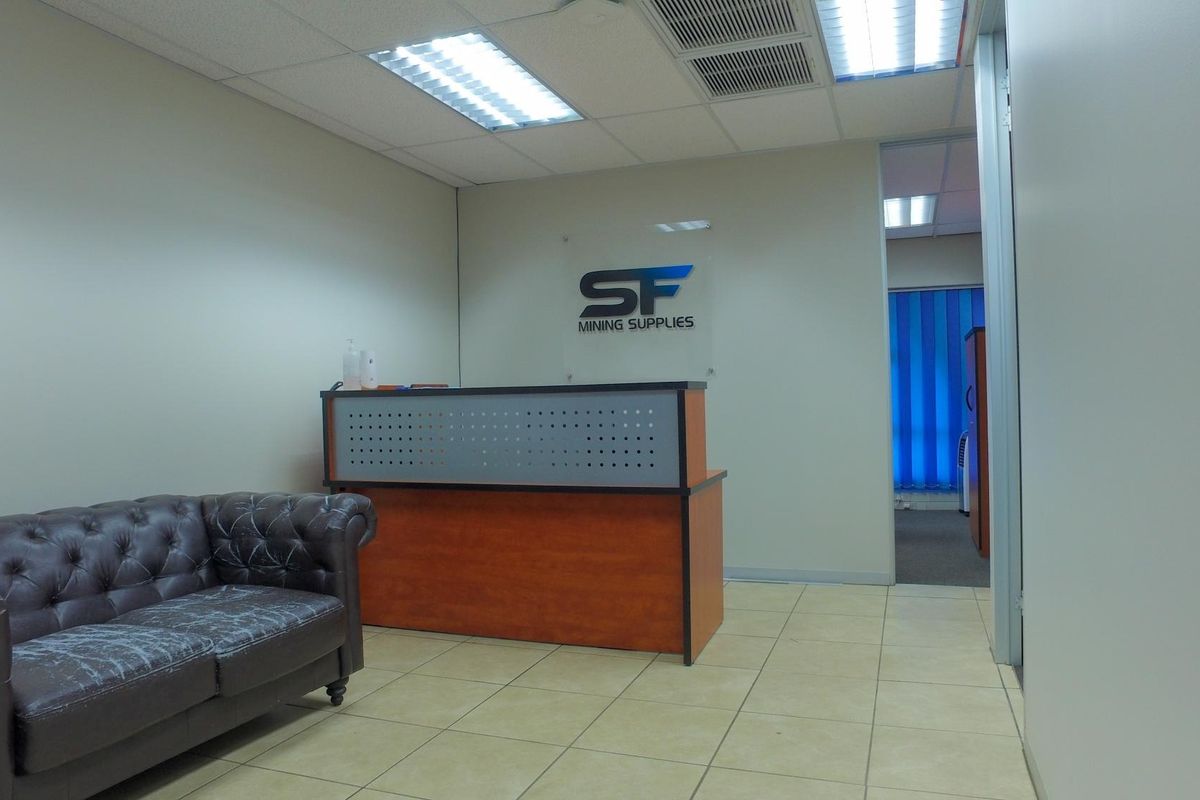 Professional office reception area featuring ceramic tile flooring, suspended ceiling with integrated lighting, and a built-in reception desk.
