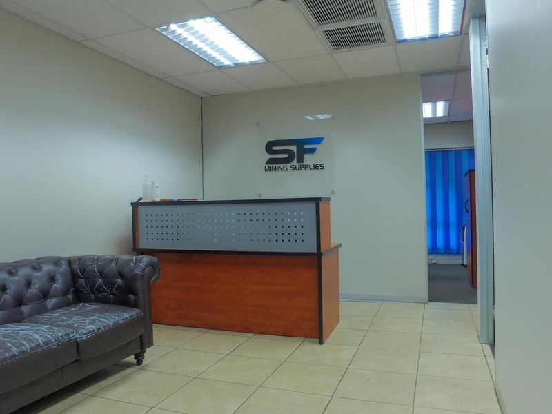 Professional office reception area featuring ceramic tile flooring, suspended ceiling with integrated lighting, and a built-in reception desk.