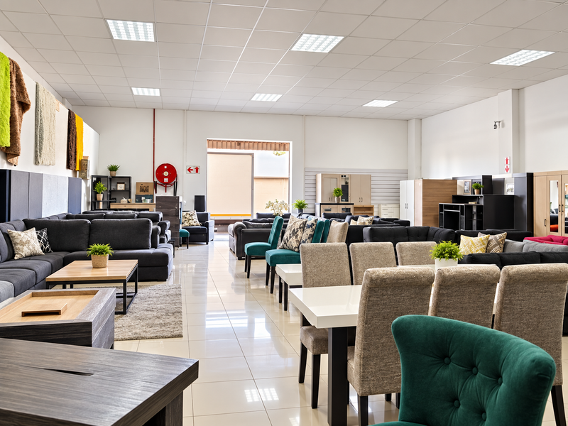 Spacious retail showroom featuring high ceilings with recessed lighting, polished tiled flooring, and a functional open-plan layout suitable for furniture display.