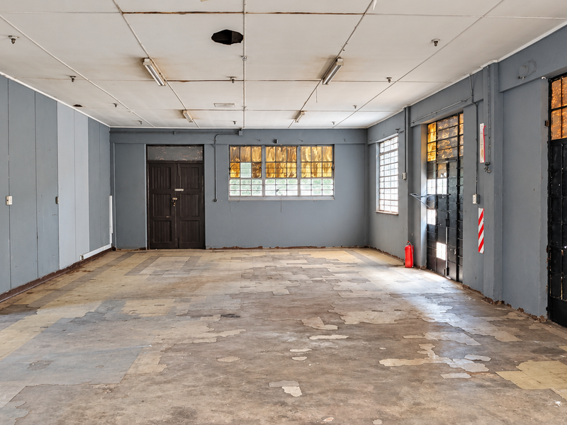 Spacious industrial open-plan area featuring high ceilings, large steel-framed windows, and durable flooring, suitable for versatile commercial or warehouse use.