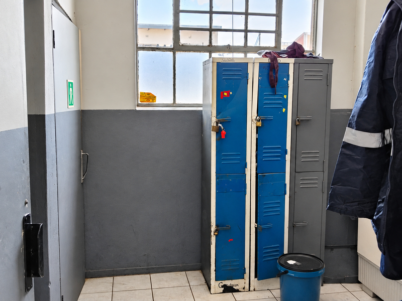A functional utility or locker room featuring industrial-style steel lockers, tiled flooring, and a large window providing natural light.