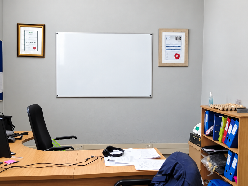 A functional office space featuring neutral walls, a whiteboard, and integrated electrical and data infrastructure.