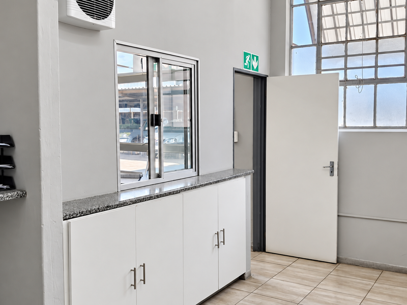 A clean, functional utility or office space featuring built-in cabinetry with granite countertops, tiled flooring, and industrial-style steel-framed windows.